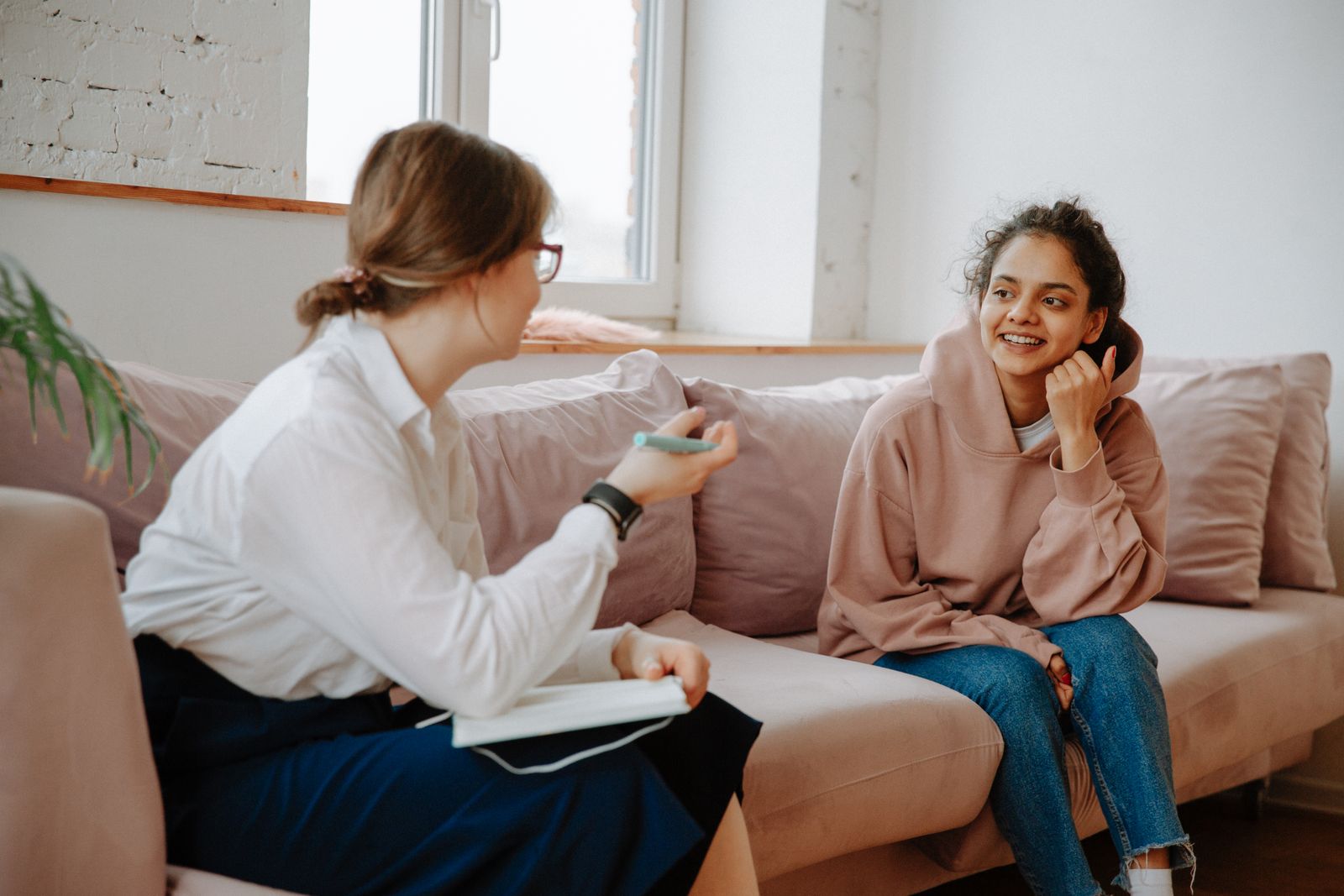 Jongere in gesprek met een hulpverlener in een huiselijke kamer